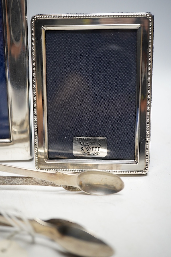 A collection of white metal and hallmarked silver to include three photo frames, a mounted glass flask, a compact, a lipstick holder, a cased pair of Victorian pepper pots, two pairs of Georgian sugar tongs and a mounted